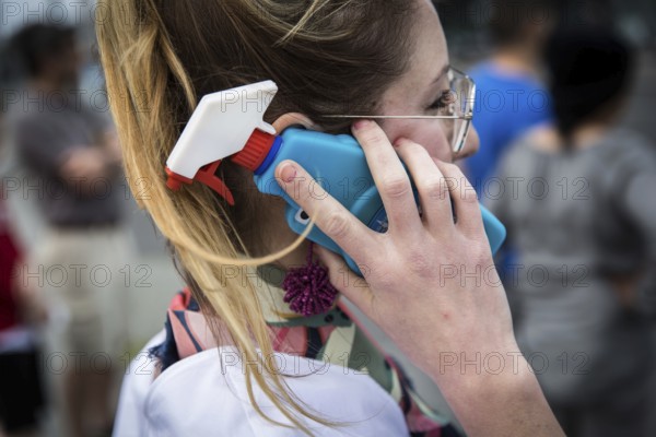DEU Germany Germany Berlin A woman talks on her smartphone with a glass cleaner tab on the cover