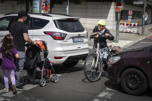 DEU Germany Germany Berlin Cyclist and pedestrian queue through heavy traffic on Klingenhoeferstrasse