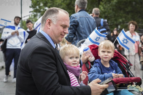 DEU Germany Germany Berlin Pro-Israel demonstration on Kurfürstendamm towards Breitscheidtplatz. Father with children, with milk bottle and mobile phone
