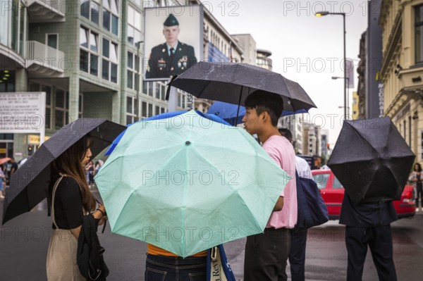 DEU Germany Germany Berlin Tourists with umbrellas at Checkpoint Charlie