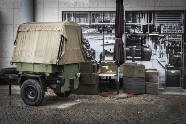 DEU Germany Germany Berlin Ammunition boxes and a military trailer in front of a photo from the Cold War era next to a cafe at Checkpoint Charlie