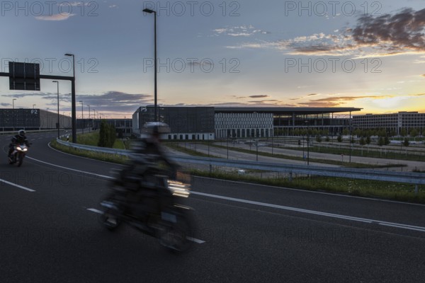 DEU Germany Germany Berlin Motorbikes pass the future BER Berlin-Brandenburg airport at sunset
