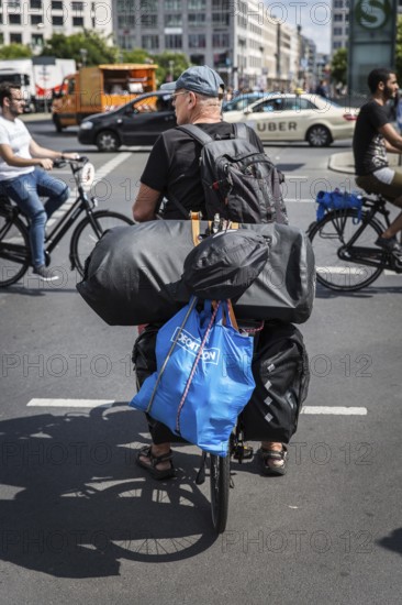 DEU Germany Germany Berlin Cyclist with numerous pieces of luggage on his bike passes Potsdamer Platz