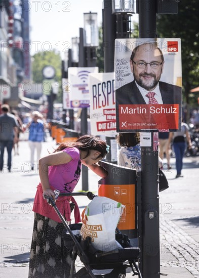 DEU Germany Germany Berlin A woman searches for recyclables in the rubbish bin in front of election posters on Wilmersdorfer Strasse