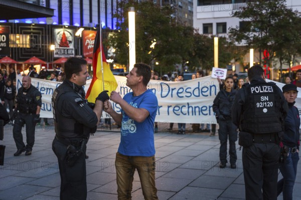 DEU Germany Germany Dresden Pegida demonstration in the city centre. Counter-demonstration in the pedestrian zone Police officer admonishes Pegida supporter who provokes with German flag