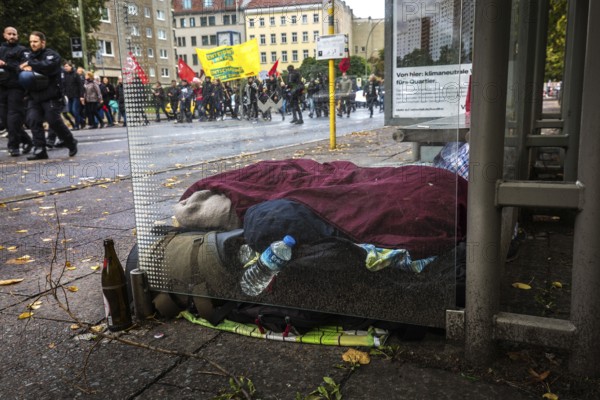 DEU Germany Germany Berlin Demonstration against rent increases and gentrification Protest march passes a homeless man sleeping in a bus stop in Kreuzberg