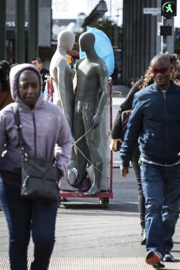 DEU Germany Germany Berlin Pedestrians crossing a street at Potsdamer Platz where mannequins are being transported in the background