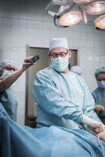 DEU Germany Germany Wittenberg Everyday life at the Paul Gerhardt Stift Protestant hospital in Luther city Wittenberg, an operation situation in which the head physician is talking on a telephone held by an assistant at the same time