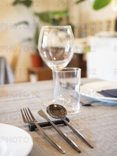 Elegant restaurant table arranging cutlery, plates, and glasses on a linen tablecloth
