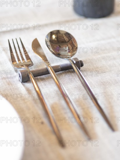 Fork, knife, and spoon balancing on a metal bolt, creating a unique table setting
