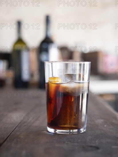 Refreshing vermouth cocktail with ice and orange on a wooden table