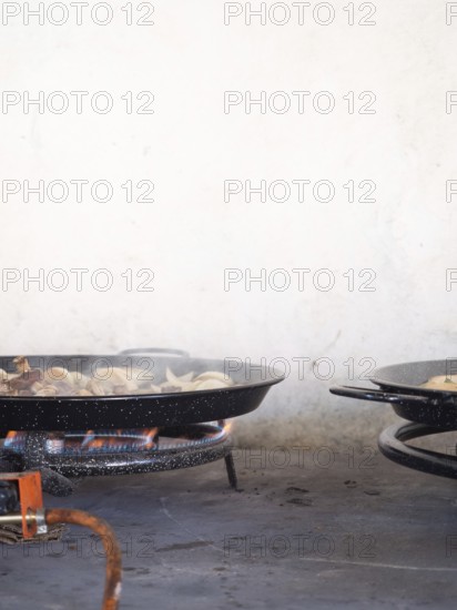 Paella pan on a gas burner cooking ingredients, preparing spanish food