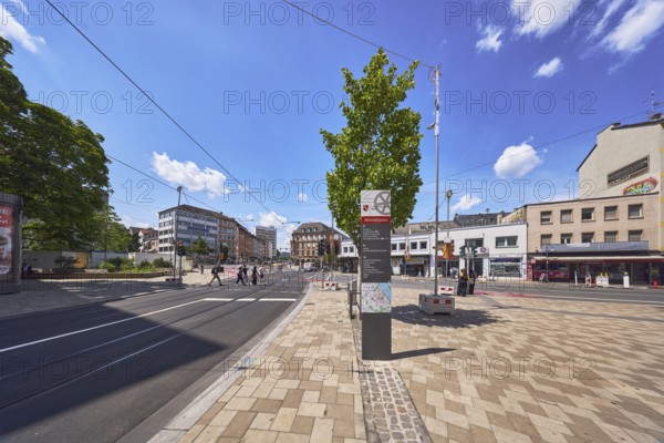Stele with location sign, traffic area, roads, square, road construction, tram tracks, overhead lines, general architecture, commercial buildings, residential buildings, concrete paving walkway, general architecture, pedestrians as a secondary motif, tree, blue sky, cumulus clouds, intersection Schillerstraße with Große Bleiche and Münsterplatz, Mainz, state capital, district-free city, Rhineland-Palatinate, Germany