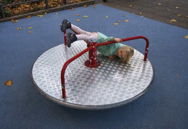 Outdoor shot, little girl, child, 4 years, blonde, playing, gymnastics on carousel, children's playground, autumn leaves, autumn, autumn, Stuttgart, Baden-Württemberg, Germany