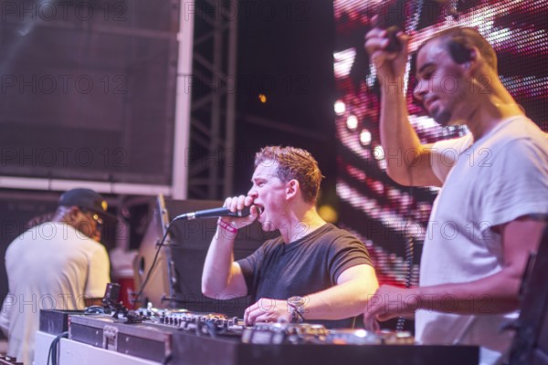 EDITORIAL and NEWS ONLY, rare moment of joint DJ back to back performance of edm dance music DJ Afrojack (person on the right) performing with DJ Hardwell (person with microphone) on DJ pult at Starbeach events festival Hersonissos, Crete, Greece, on 17. July 2017