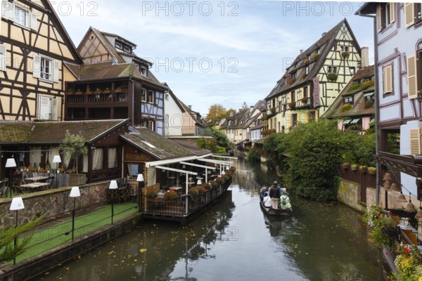 Traditional houses along a river, here called the little Venice, with tourists visiting Colmar on a boat, Alsace, France