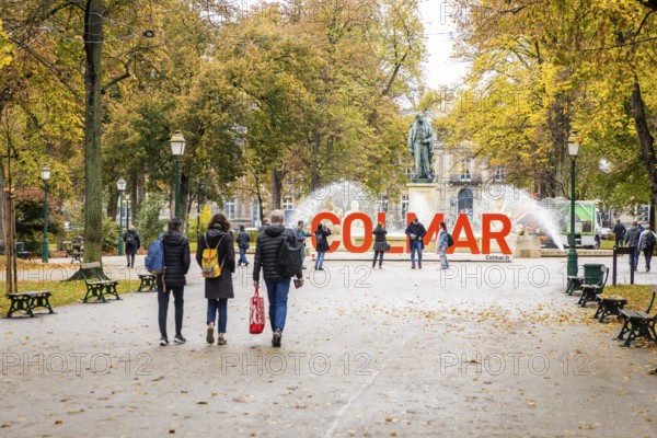 Tourists walking around the red lettering in the square Rapp of the city of Colmar, Alsace, France