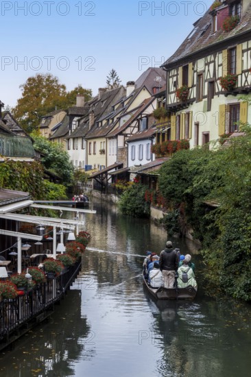 Traditional houses along a river, here called the little Venice, with tourists visiting Colmar on a boat, Alsace, France
