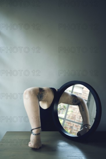 Portrait of a woman with a mirror, interior view, arm in front of the mirror, head covered