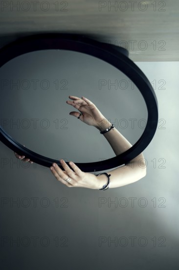 Portrait of a woman behind a mirror, hand in front of the mirror, interior view