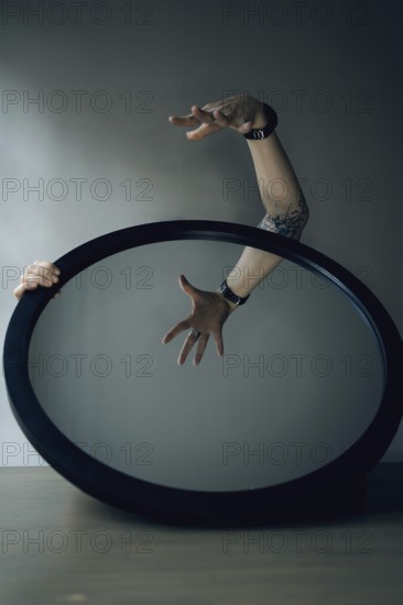 Portrait of a woman behind a mirror, interior view, hand in front of the mirror