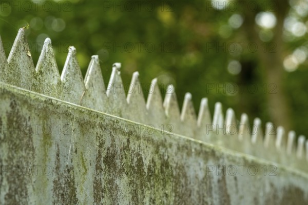 Borken, NRW, Germany, Metal security fence with sharp spikes against green bokeh creating a protective barrier