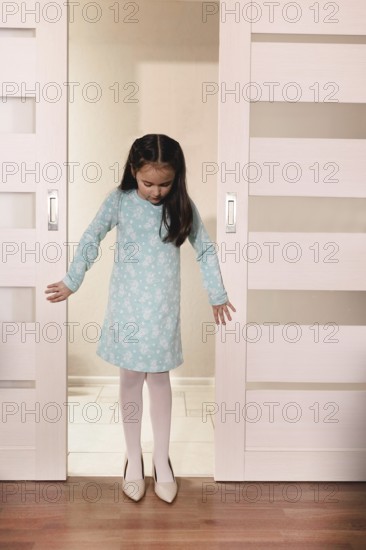 Young child wearing oversized high heels, imitating adult with fascination.Belarus