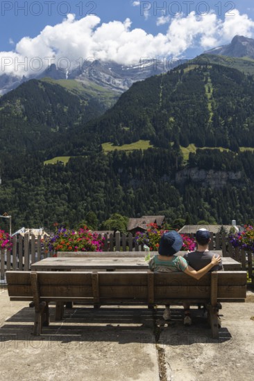 A couple sitting on a bench is enjoying the view on the mountains in Champery, a village in Switzerland by the French border