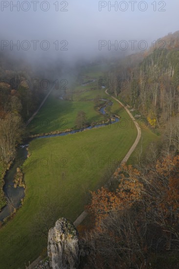 Autumn landscape with rising fog over the Grosse Lauter river loop in Lautertal at sunrise. View from above of the picturesque valley with colorful deciduous forest and rolling hills, Großes Lautertal, Baden-Württemberg, Germany