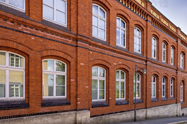 Classic red brick façade of a building with white windows under a blue sky, brick façade of Arnstadt in Thuringia