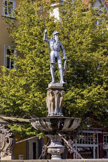 Metal statue of a warrior on a fountain surrounded by green trees, statue and monument in the old town of Arnstadt in Thuringia
