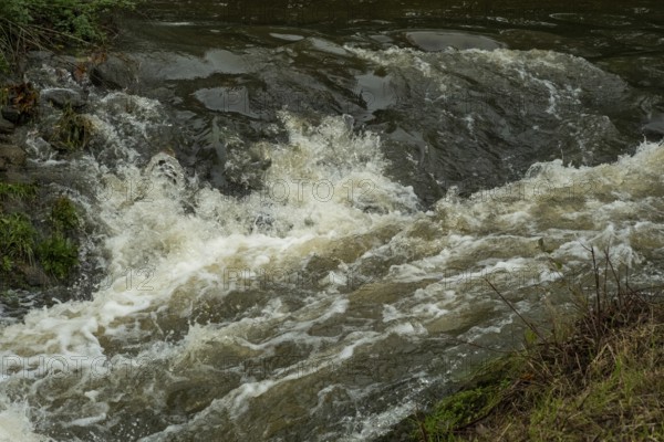 Borken-Hoxfeld, NRW, Germany, Water cascades over rocks in a peaceful environment, creating frothy waves and gentle splashes. The scene captures the beauty of nature's movement and tranquility