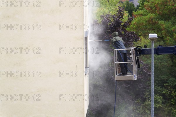 Unrecognizable man cleaning facade surface from lifting platform with high pressure stream of water Prague, Czech republic