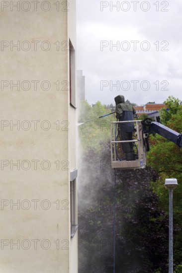 Unrecognizable man cleaning facade surface from lifting platform with high pressure stream of water Prague, Czech republic
