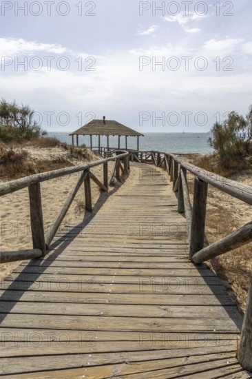A wooden walkway leads to a cabin by the sea. View of the Atlantic Ocean from the beach of the Pinar de la Almadraba Nature Reserve, Pinares De Rota, Rota, Cadiz, Andalucia, Spain