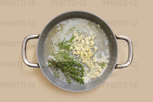 Butter and olive oil are heating in a pan with finely chopped garlic, ginger and fresh thyme and rosemary. The fragrances blend together, creating a rich base for various dishes