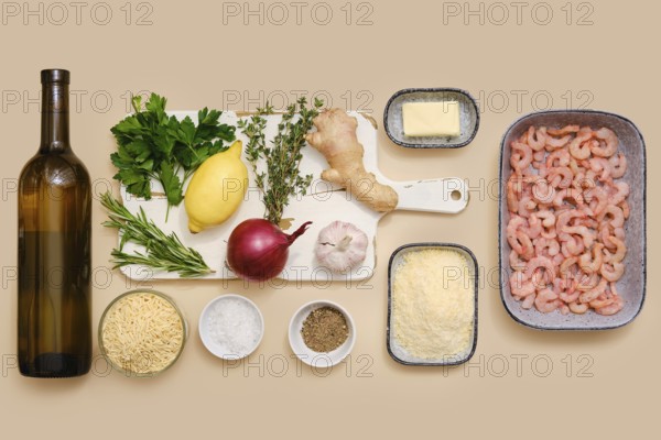 Ingredients for making risoni pasta with shrimp including white wine, parsley, lemon, thyme, rosemary, ginger, garlic and grated parmesan cheese. Flat lay, top view