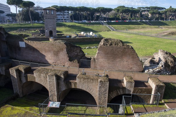 View of location from in the foreground ruins of former stands around south bend of on Circus Maximus venue of chariot races, in the middle medieval tower Torre della Moletta, part of medieval building ruin from the Middle Ages in the archaeological complex of Circus Maximus, Rome, Lazio, Italy