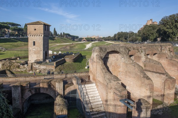 View of location from in the foreground ruins of former stands around south bend of on Circus Maximus venue of chariot races, left medieval tower Torre della Moletta, part of medieval building ruin from the Middle Ages in the archaeological complex of Circus Maximus, Rome, Lazio, Italy