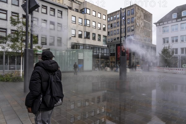 Digital water feature, Blue Cloud water installation on Husemanplatz in downtown Bochum, water mist is sprayed from 4 metal masts, which, in conjunction with the circular water surface, is intended to cool the surrounding area when it is hot, colored light images are projected into the water mist via projectors, part of the transformation of Husemanplatz
