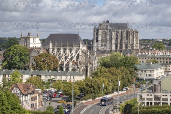 View of the city center, taken from the Table d'Orientation de Beauvais. In the center, the Gothic Cathédrale Saint-Pierre de Beauvais and the Saint-Etienne church dominate the skyline. The image shows a mixture of urban development and green spaces crossed by a main road or under a cloudy sky in Beauvais, Oise department (60), Hauts-de-France region, France