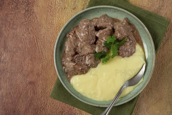 Liver beef stroganoff with mashed potatoes, table setting in green tones, homemade