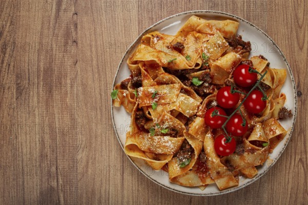Pappardelle pasta with bolognese sauce, topped with parmesan cheese and cherry branch, homemade, no people