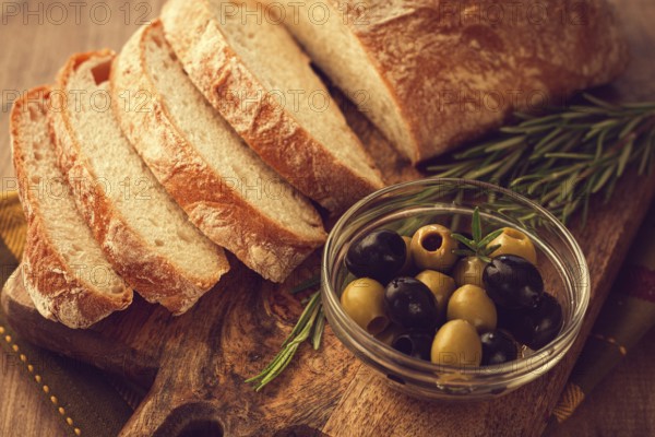 Sliced ciabatta, on a chopping board, with rosemary and olives, Italian bread, close-up, Italian cuisine, breakfast, no people