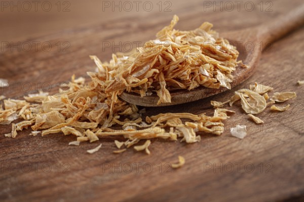 Smoked onion flakes, on a wooden spoon, wooden table, close-up