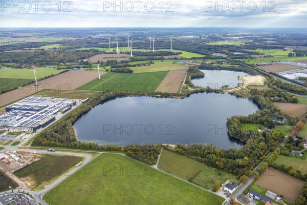 Aerial view, Tricor Werk packaging company at Sandgrube Höster Feld, Weeze, Lower Rhine, North Rhine-Westphalia, Germany, DE, roof with solar panels, Europe, commercial space, commercial area, commercial property, commercial location, commercial use, Goch, industrial location, aerial photography, aerial photography, photovoltaic system, lake, solar, solar system, solar roof, solar energy, solar panels, solar power location, overview, bird's eye view, birds-eyes view, overview