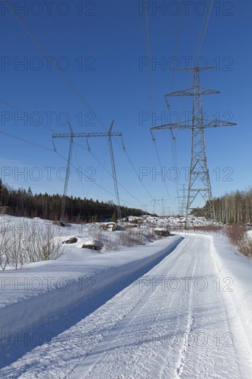 High-voltage power lines and road in sunny winter weather with snow on the ground, Loviisa, Finland