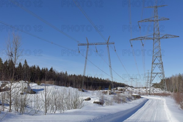 High-voltage power lines and road in sunny winter weather with snow on the ground, Loviisa, Finland