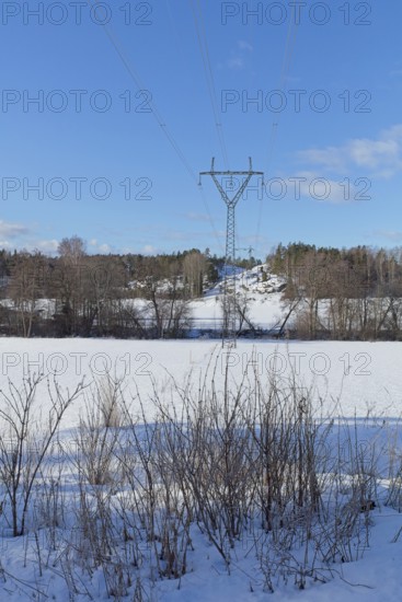 High-voltage power lines in sunny winter weather with snow on the ground, Pikkala, Finland