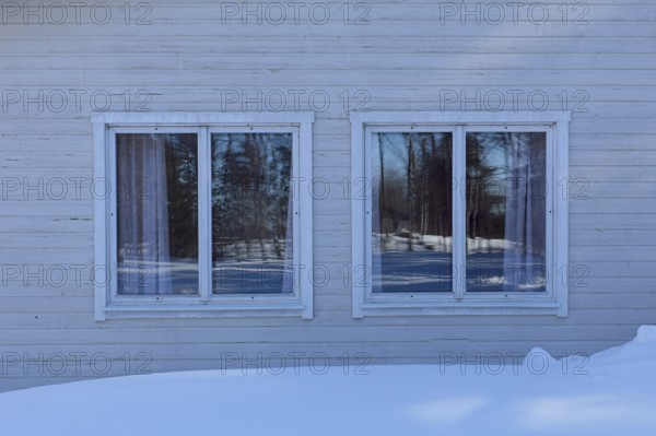 Two windows on a old wood building in winter with snow on the ground, Vastila, Finland
